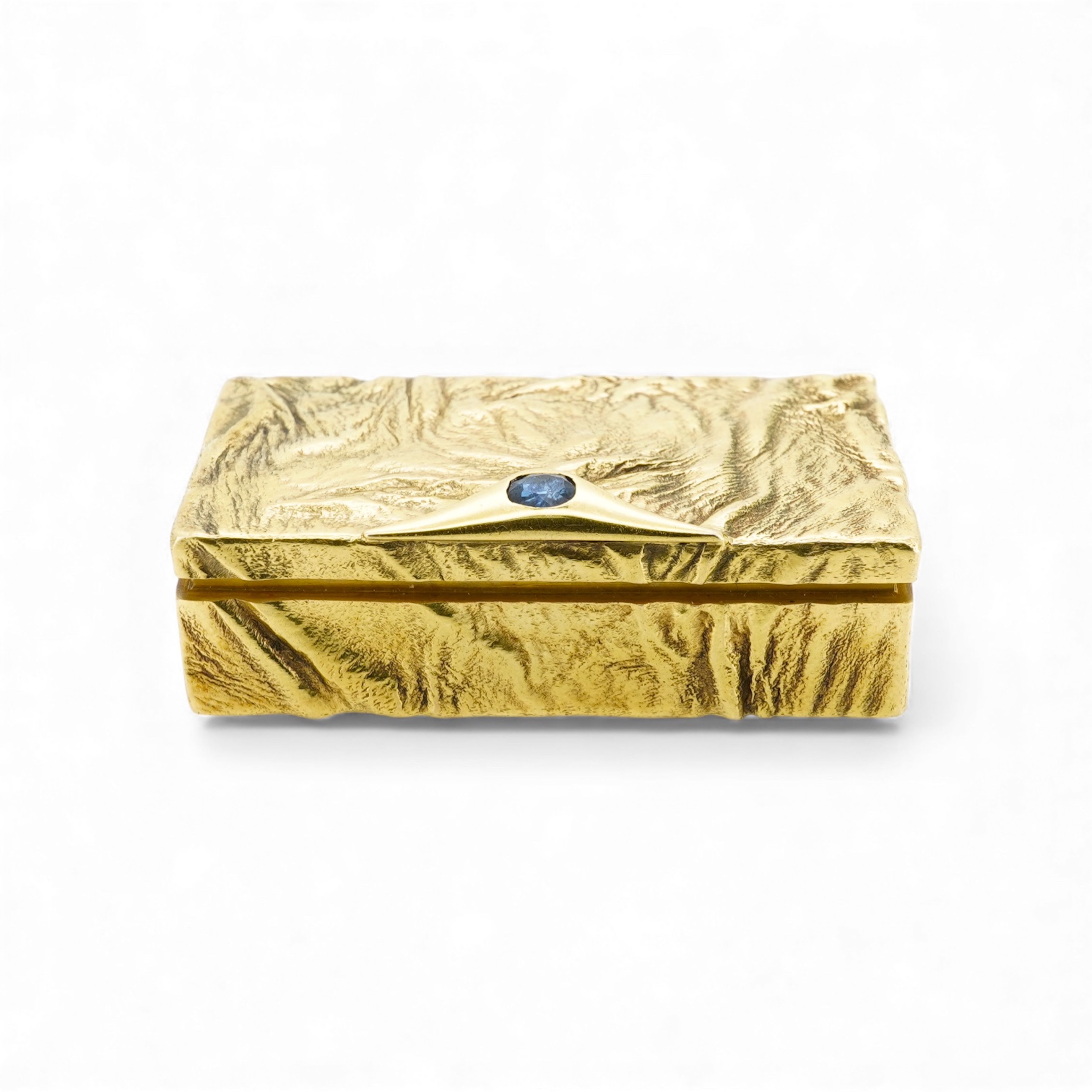 Dunhill, an attractive 9ct gold and sapphire snuffbox, circa 1973, the rectangular box of samorodok finish, the hinged lid set with a foil-backed oval sapphire, measuring approximately 5.1 x 2.7 x 1.6cm, signed Dunhill L